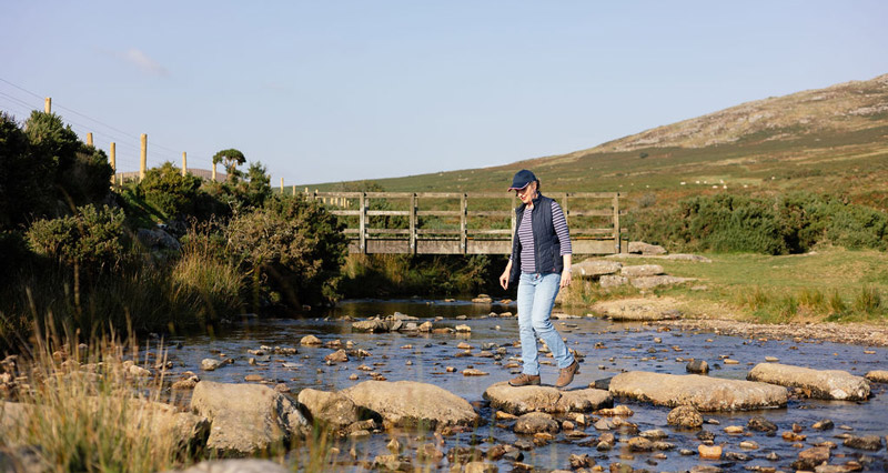 Caroline walking on stones of Dartmoor river
